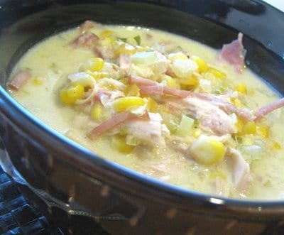 A bowl of chicken corn chowder with shredded chicken and corn.