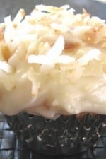 A Coconut Cupcake topped with toasted coconut and cream cheese frosting.
