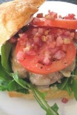 A Double Mozzarella Turkey Burger on a ciabatta roll with arugula, artichoke remoulade, tomatoes, pancetta, and mozzarella.