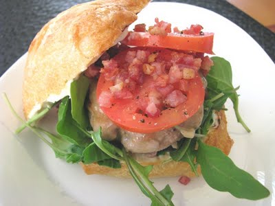 A Double Mozzarella Turkey Burger on a ciabatta roll with arugula, artichoke remoulade, tomatoes, pancetta, and mozzarella.