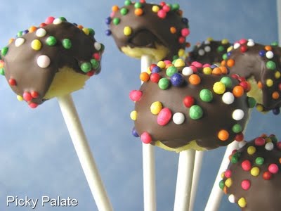 6 Cheesecake Pops topped with melted chocolate and round sugar balls.
