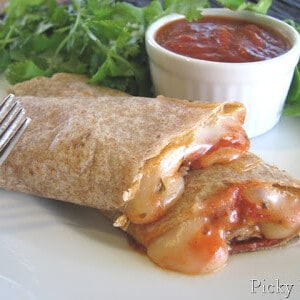 Pizza Roll Ups on a plate next to a bowl of marinara sauce.