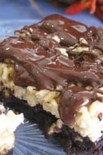 A piece of Crispy Caramel Brownie Treats with a brownie layer on the bottom, a Rice Krispy layer above it, and a drizzle of chocolate on top.