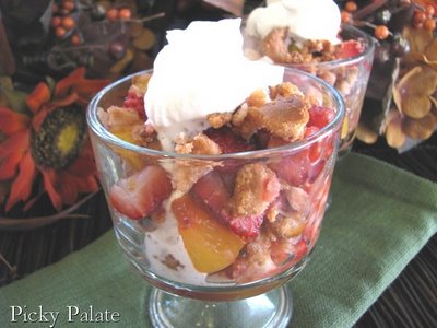 A glass full of Peach Berry Bagel Crisp topped with whipped cream.