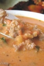 A bowl of Creamy Tomato Basil and Italian Sausage Soup with a spoon.