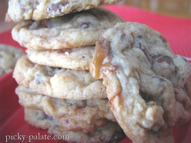 A stack of chewy Butterfinger and Milky Way Chocolate Chunk Cookies with one tilted at an angle against the stack.