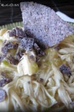 A plate of Green Chicken Chili served over rice and topped with blue corn tortilla chip crumbles.