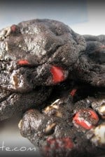 A pile of rich Chocolate Cherry Chip Cookies with bursts of red cherry chips and white chocolate chips mixed throughout.