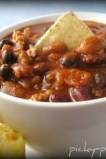 A bowl of easy ground turkey chili served with cornbread muffins.