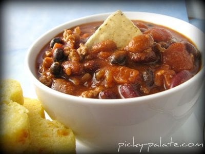 A bowl of easy ground turkey chili served with cornbread muffins.