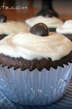 Four Chocolate Fudge Junior Mint Cupcakes topped with frosting and a junior mint wrapped in a silver cupcake liner.