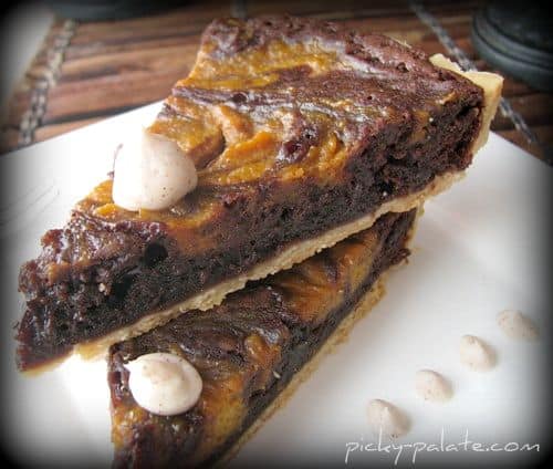Two slices of pumpkin pie swirled brownie tart with cinnamon cream on top.