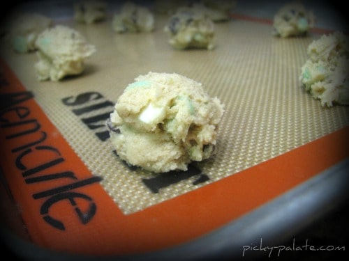Balls of mint chocolate chip cookie dough on a silpat.