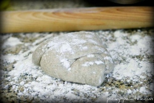 A ball of pizza dough on a floured work surface.