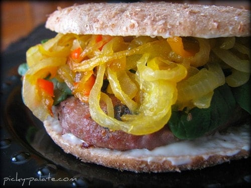 A caramelized onion turkey burger on a sandwich thin and stuffed with yellow sweet peppers