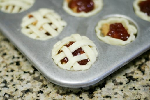 Close up of the lattice crust on peanut butter and jelly mini pies in a muffin tin.