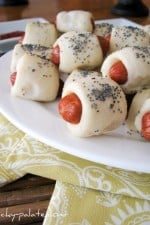 Plate of piglets in a blanket with poppy seeds on top.