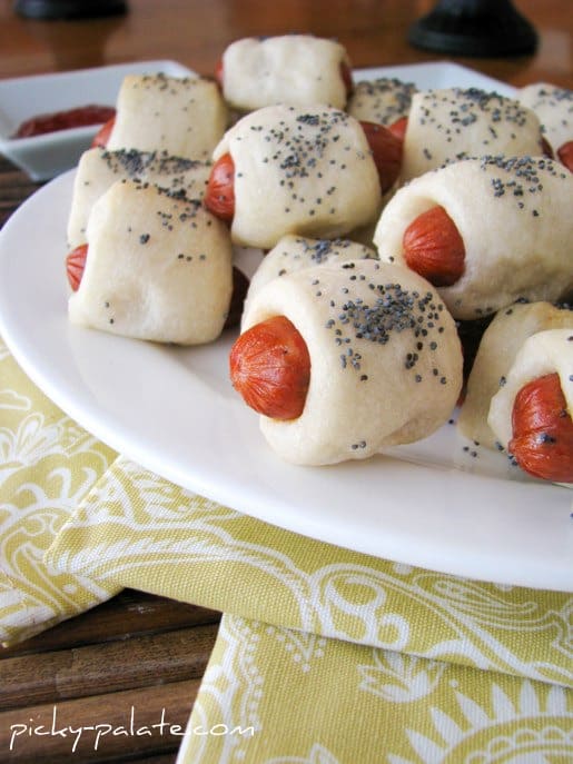 Plate of piglets in a blanket with poppy seeds on top.