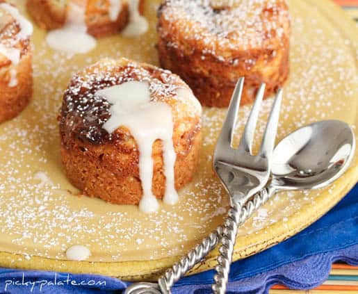 Peanut butter and jelly cheesecake bites drizzled with vanilla glaze next to a fork and spoon.