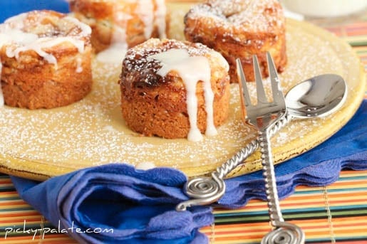 Peanut butter and jelly cheesecake bites drizzled with vanilla glaze next to a fork and spoon.