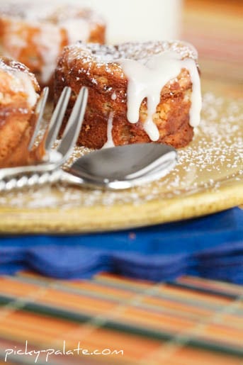 Peanut butter and jelly cheesecake bites drizzled with vanilla glaze next to a fork and spoon.