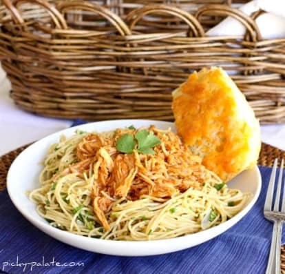 A Bowl of BBQ Chicken Spaghetti with a Piece of Cornbread in Front of a Wicker Basket