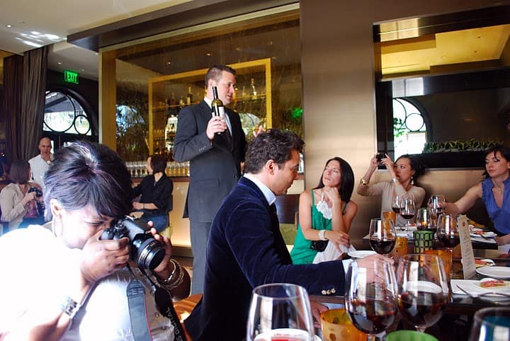 The Server Holding a Bottle of Wine While Shelisa Takes a Photo of Her Full Glass