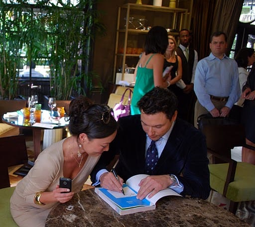 Sarah and Rocco Looking at Rocco's Cookbook as He Signs It