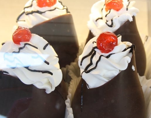 Four Chocolate Pastries with Whipped Cream, Chocolate Sauce and a Cherry on Top