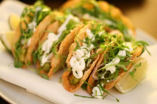 Five Lobster Tacos on a Plate with Lime Slices