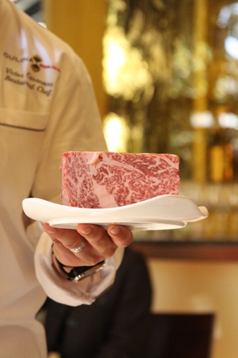 A Slab of Kobe Beef on a Fancy White Plate Being Held by Chef Victor