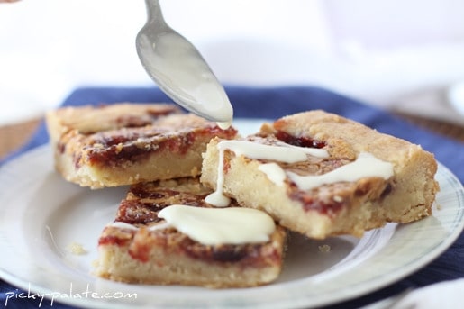 Peanut butter and jelly shortbread cookie bars are drizzled with glaze.