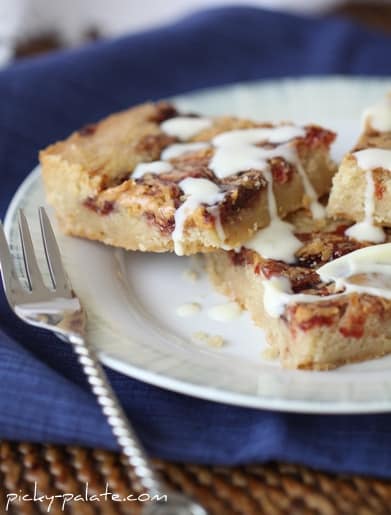 Peanut butter and jelly shortbread cookie bars drizzled with glaze on a plate.