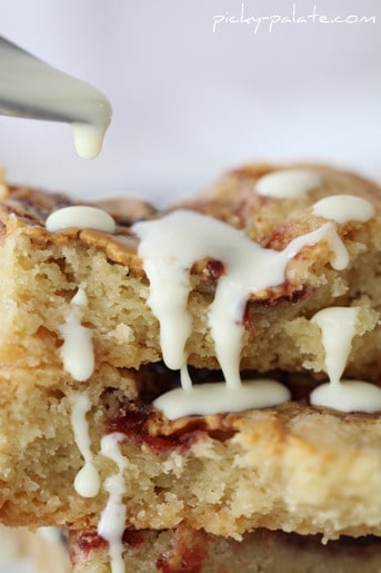 Close up of peanut butter and jelly shortbread cookie bars being drizzled with glaze.