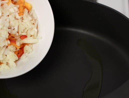 Veggies are added into a skillet.