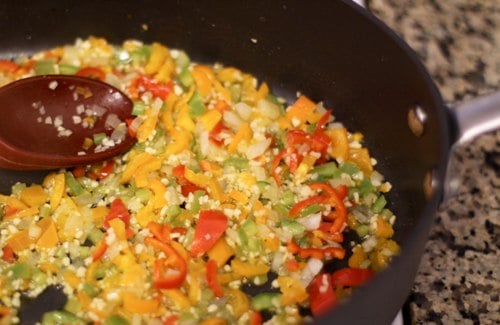 Veggies sauteed in a skillet with a wooden spoon.