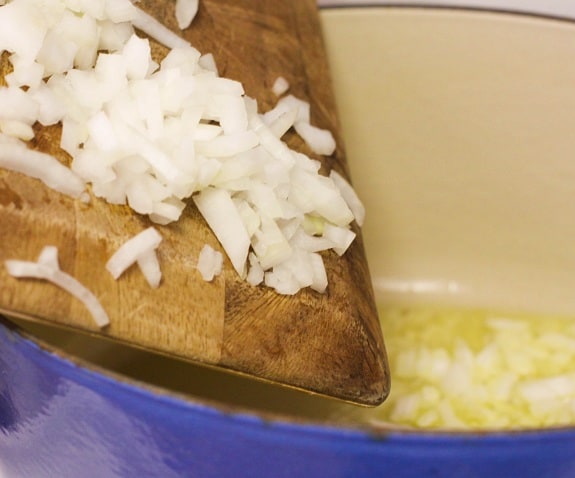 Chopped Onions Being Transferred From the Cutting Board to the Pot