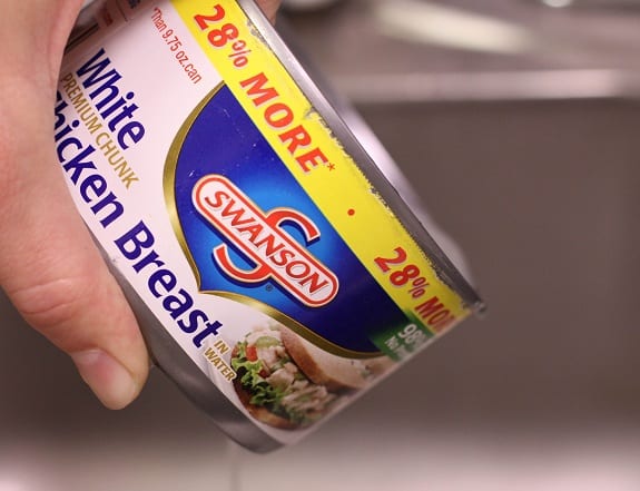 A Hand Holding a Can of Swanson's White Chicken Breasts