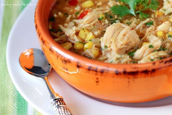 A Bowl of BBQ Chicken Pizza Soup on a Plate with a Spoon