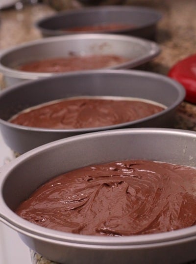 Four cake pans filled with chocolate cake batter.