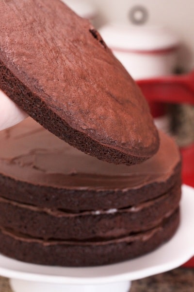 Chocolate cake layers are placed on top of one another with chocolate icing in between.