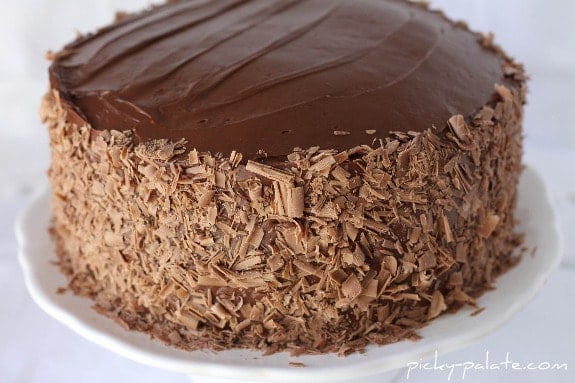 A four layer chocolate cake frosted and decorated with chocolate shavings.