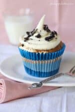 A Fluffer Oreo Cupcake on a plate topped with a swirl of marshmallow frosting and crumbled Oreos