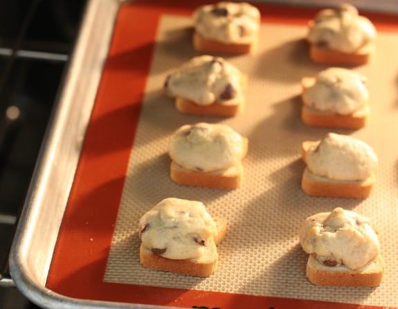 Mini chocolate chip sandwiches in rows on a silpat baking sheet.