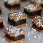 Oreo Cheesecake Pretzel Bites topped with white sprinkles on parchment paper