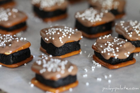 Oreo Cheesecake Pretzel Bites topped with white sprinkles on parchment paper