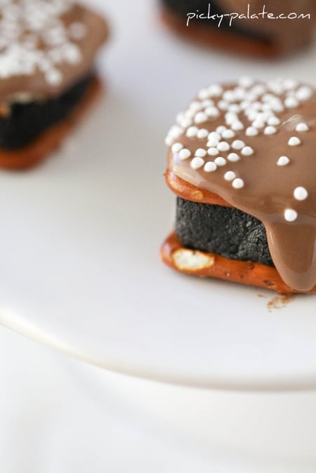 Close up of Oreo Cheesecake Pretzel Bites drizzled with chocolate and topped with white nonpareils.