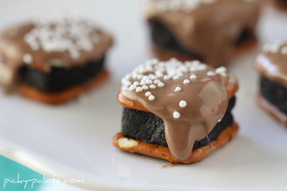 Close up of Oreo Cheesecake Pretzel Bites drizzled with chocolate and topped with white nonpareils.