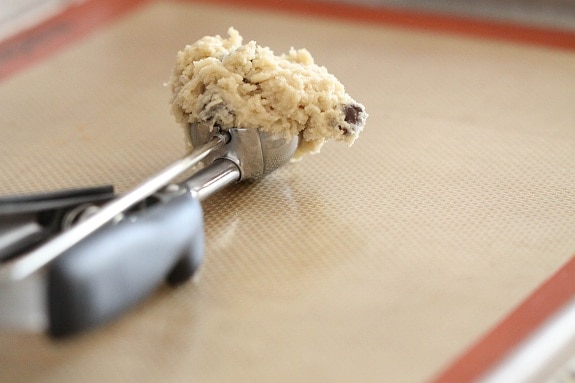 Cookie dough in a cookie scoop, laying on a baking mat.