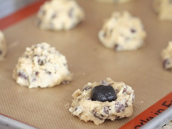 Chocolate chip cookie dough with an Oreo truffle in the center, next to rolled cookie dough balls.